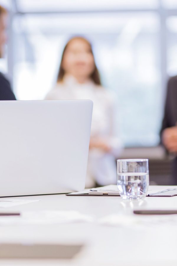 glass-water-with-laptop-table-front-businesspeople-background